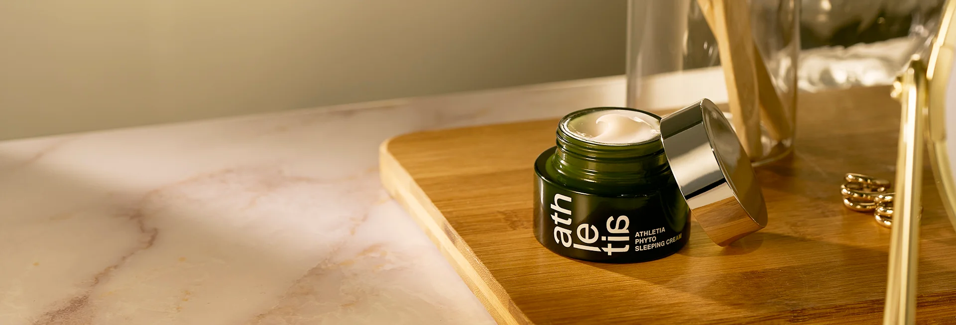 Athletia Phyto Sleeping Cream in a green jar with a silver lid placed on a wooden tray, part of the campaign offering a complimentary Core Balance Skincare Duo Trial Size Set with purchase.